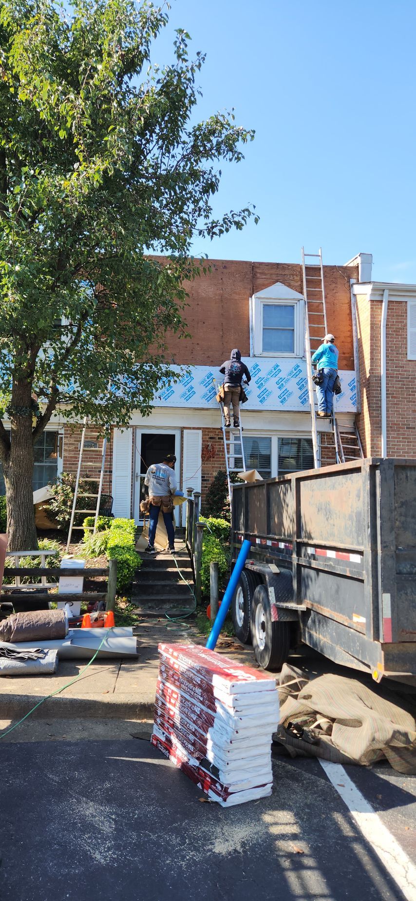A group of men are working on the roof of a house.