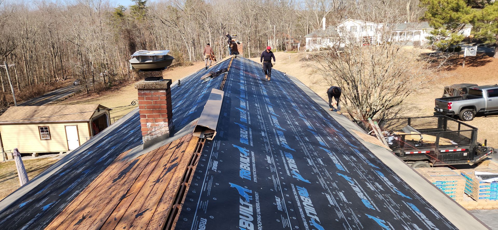 A group of people are working on the roof of a house.