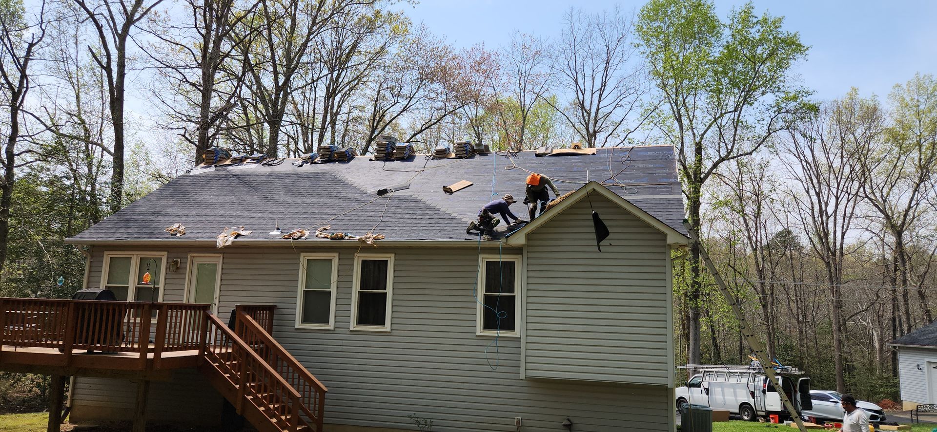 A group of people are working on the roof of a house.