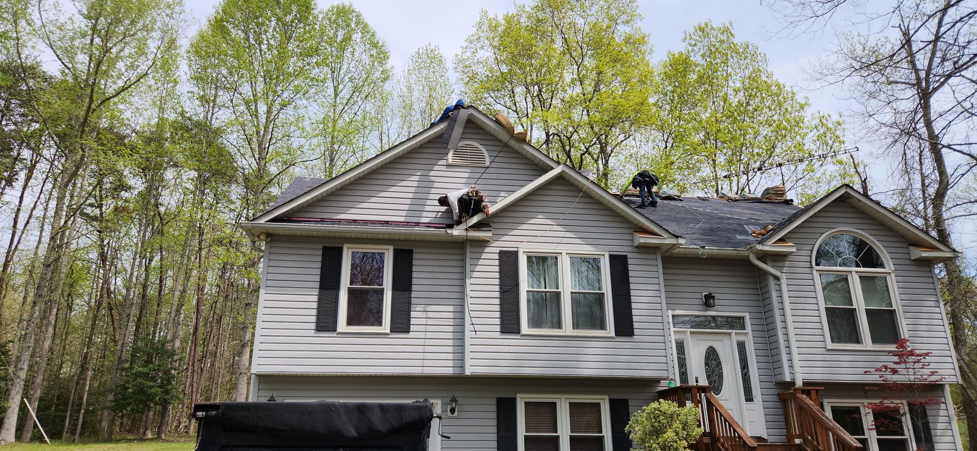 A large white house with a roof that has been damaged by a storm.