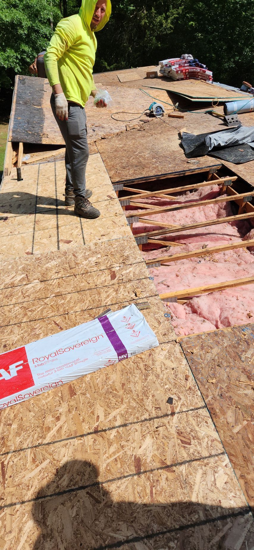 A man is standing on top of a wooden roof.