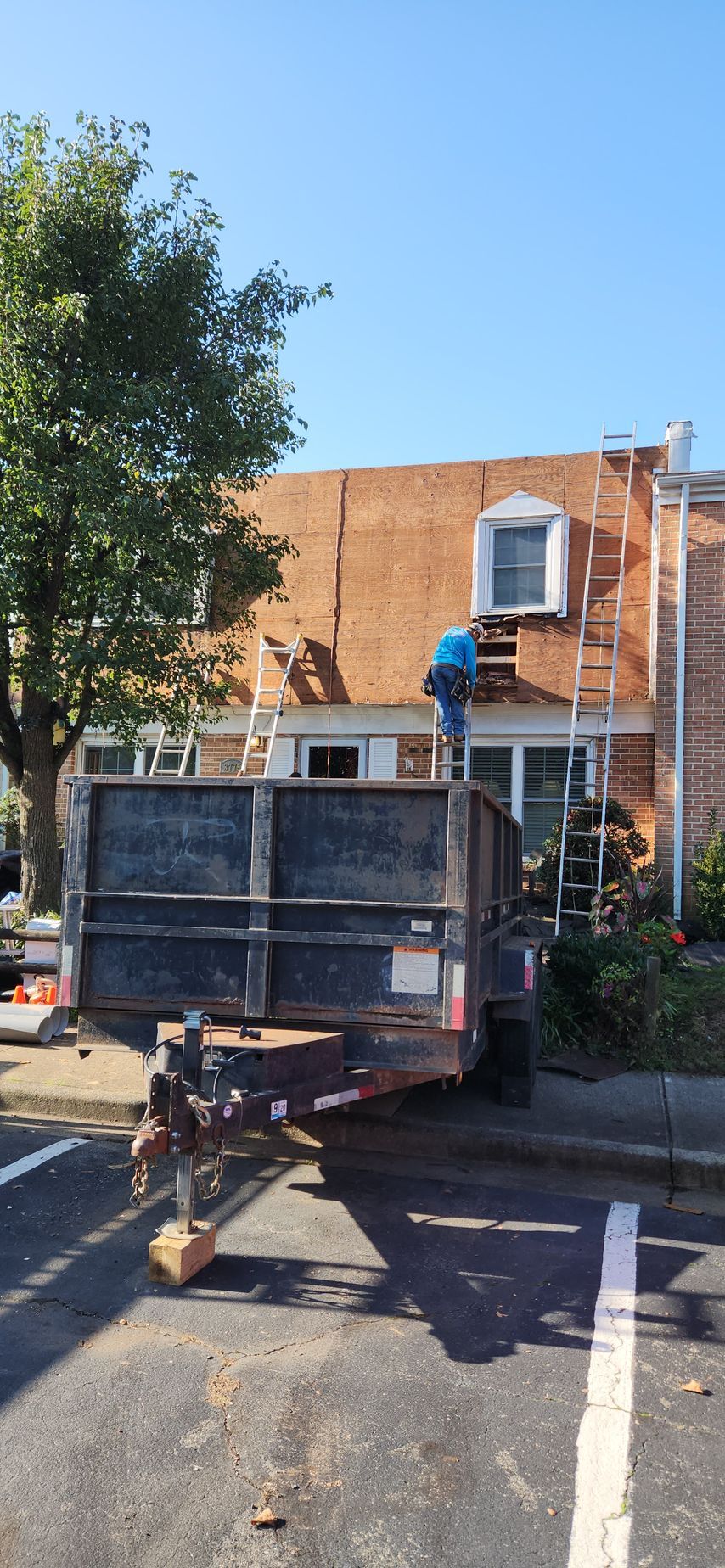 A dumpster is parked in front of a brick building.