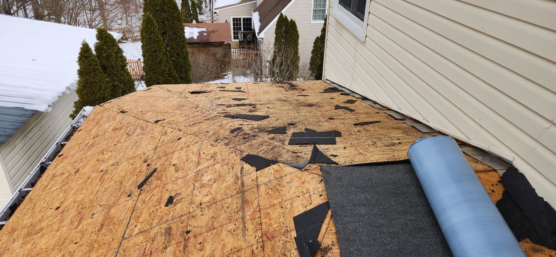 A roof with a roll of shingles on it is being repaired.