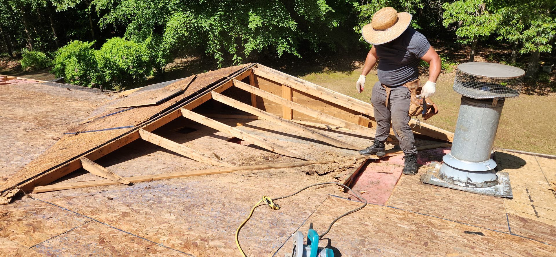 A man in a hat is standing on top of a roof.