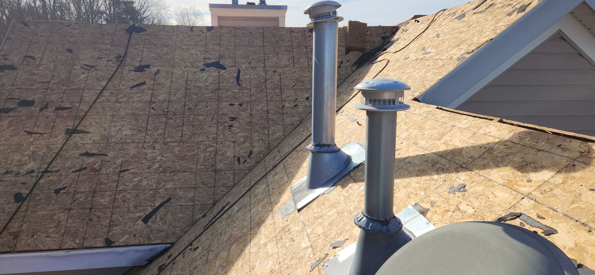 There are two chimneys on the roof of a house.