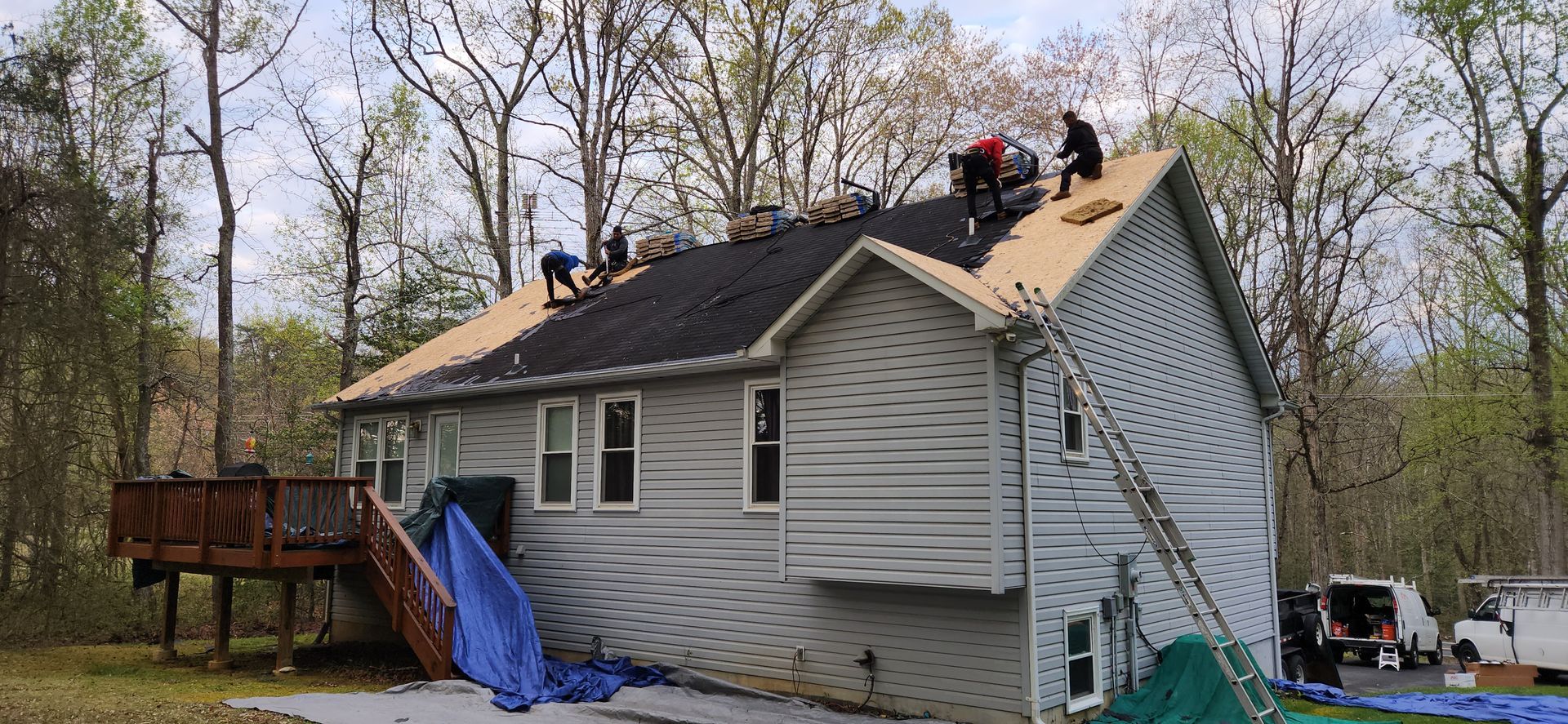 A group of people are working on the roof of a house.