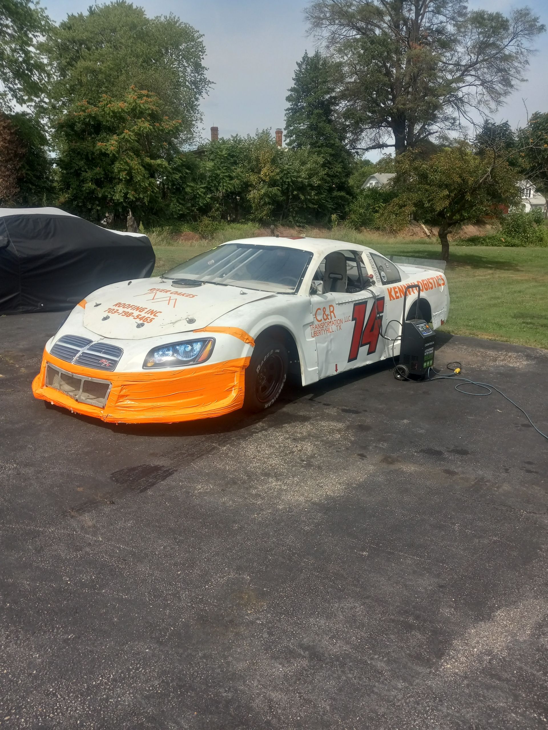 A white and orange race car is parked in a parking lot.