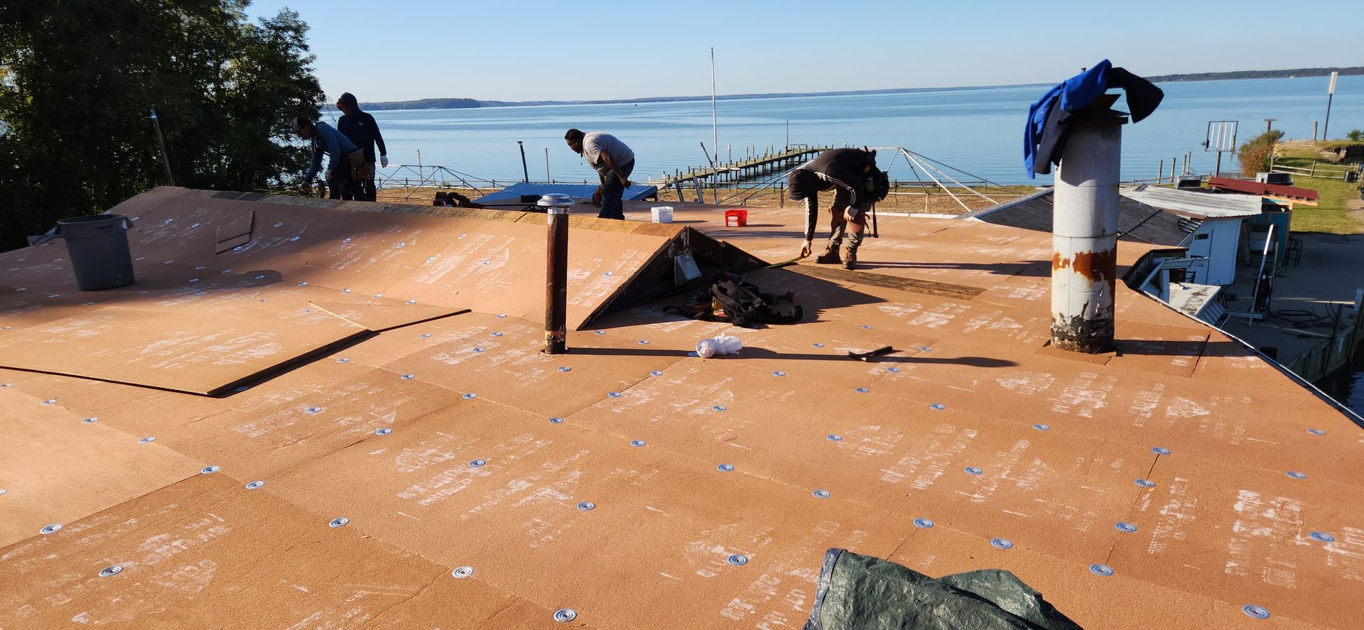 A group of people are working on a roof overlooking a body of water.
