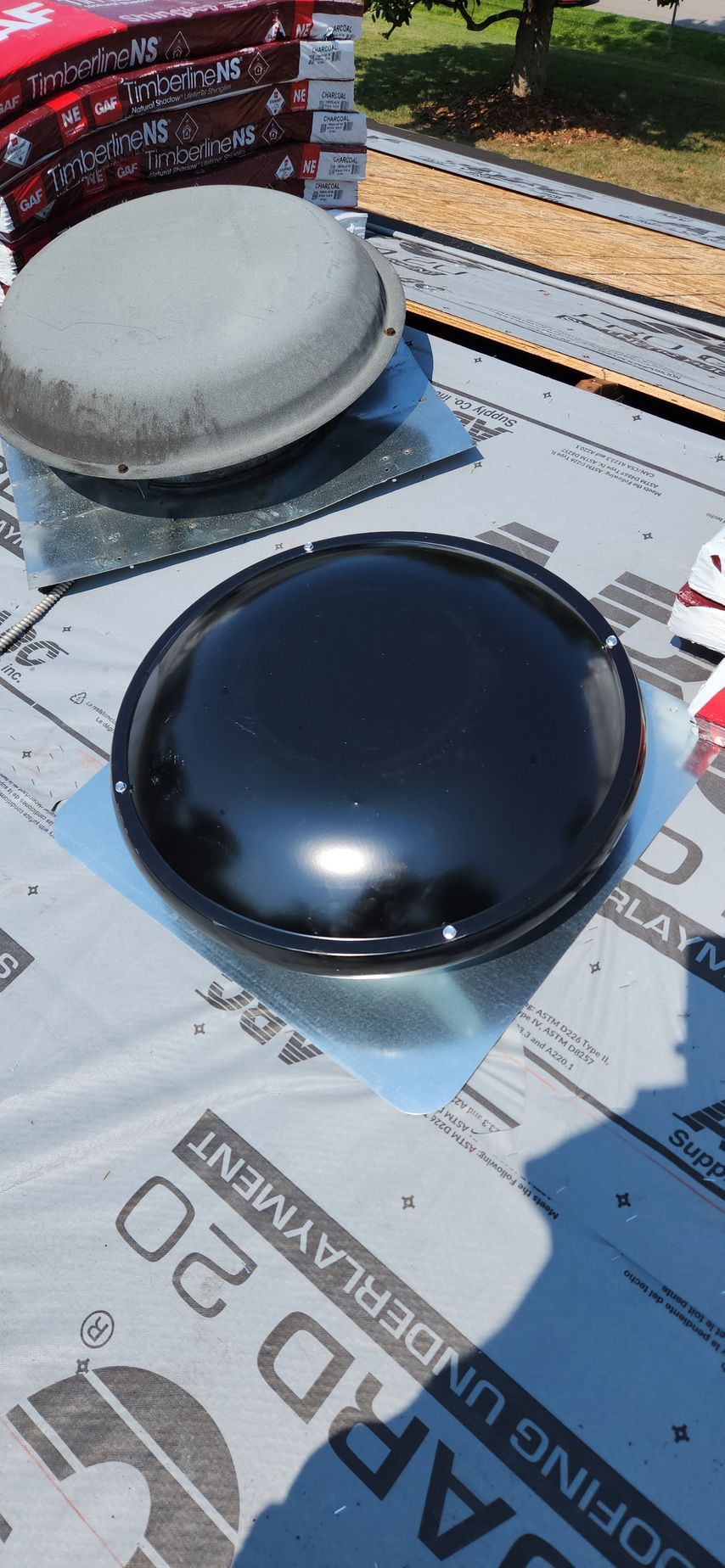 A black roof vent is sitting on top of a roof.