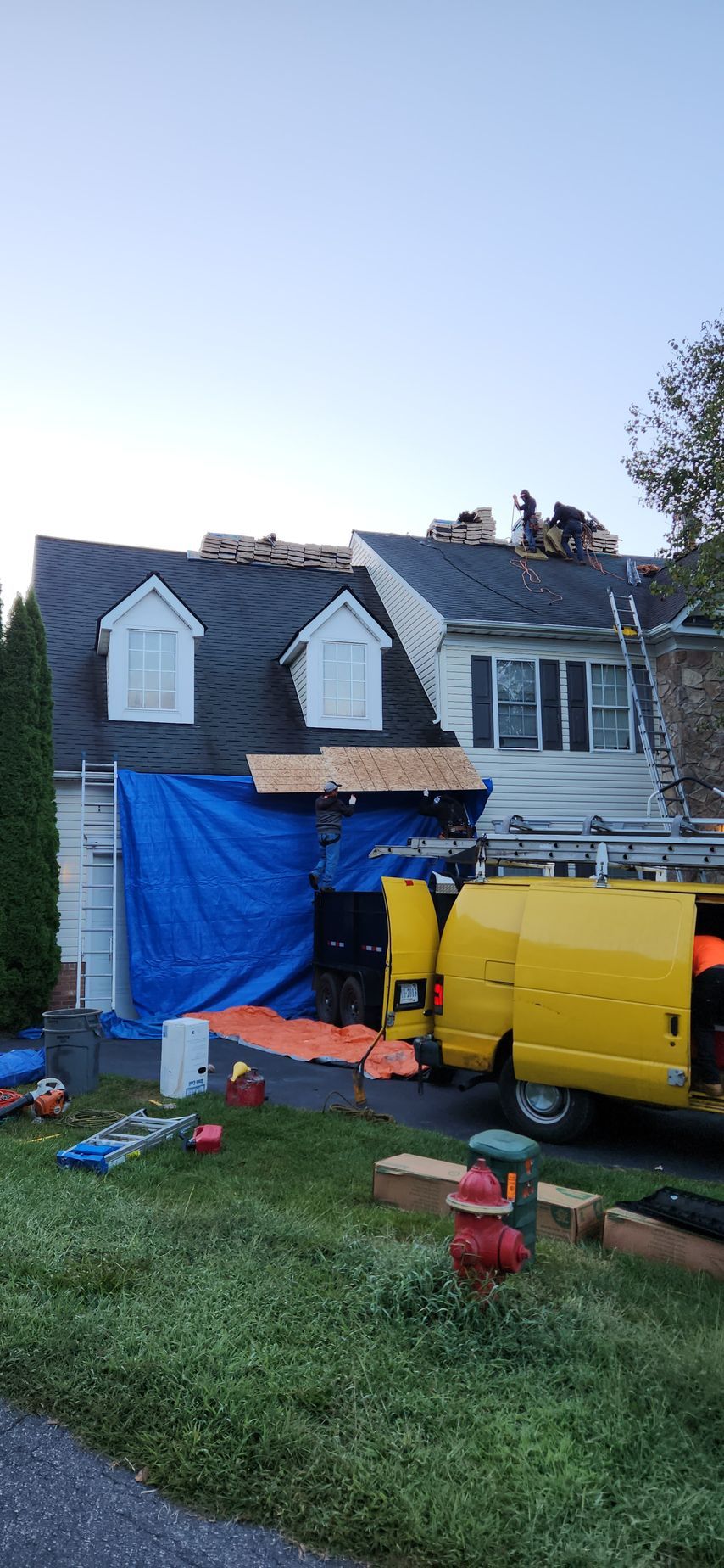 A yellow van is parked in front of a house under construction.