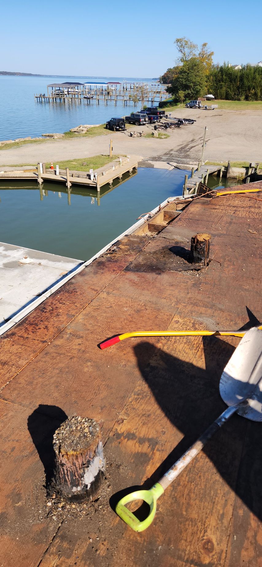 A shovel is sitting on top of a rusty roof next to a body of water.