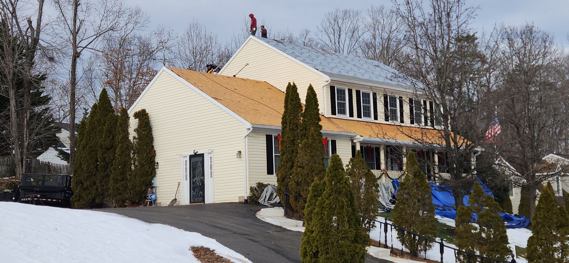 A house with a roof that is being installed in the snow.