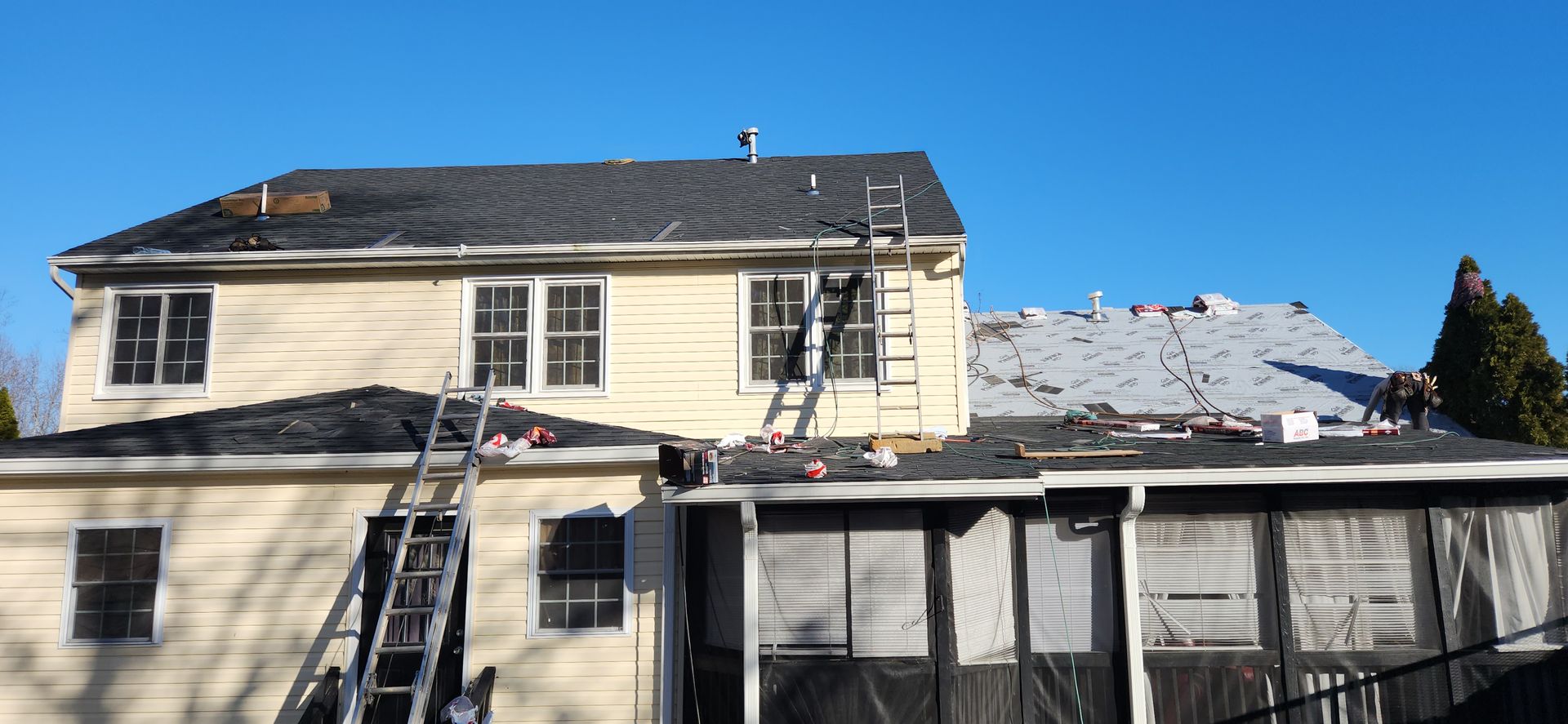 A house with a ladder on the side of it is being remodeled.