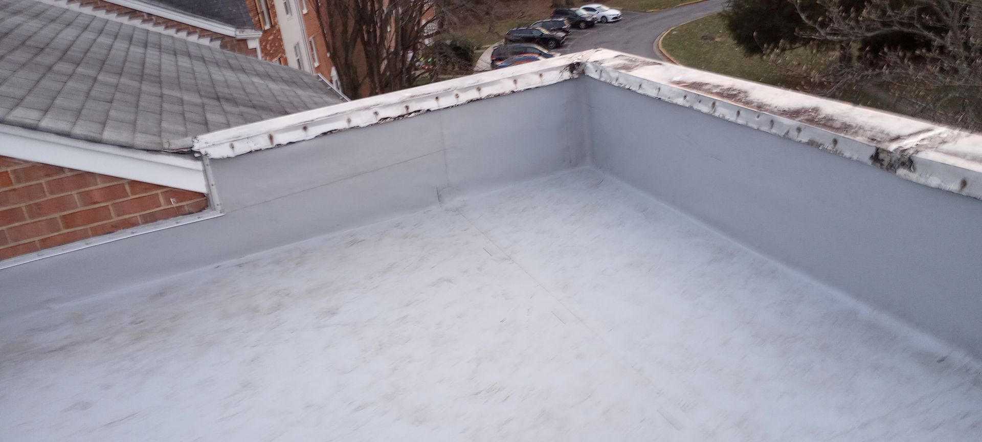 A roof with a white roof and a brick building in the background.