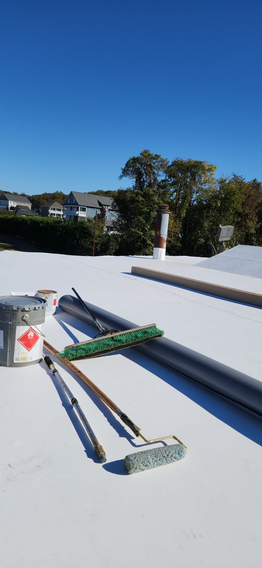 A white roof with tools on it and a blue sky in the background.