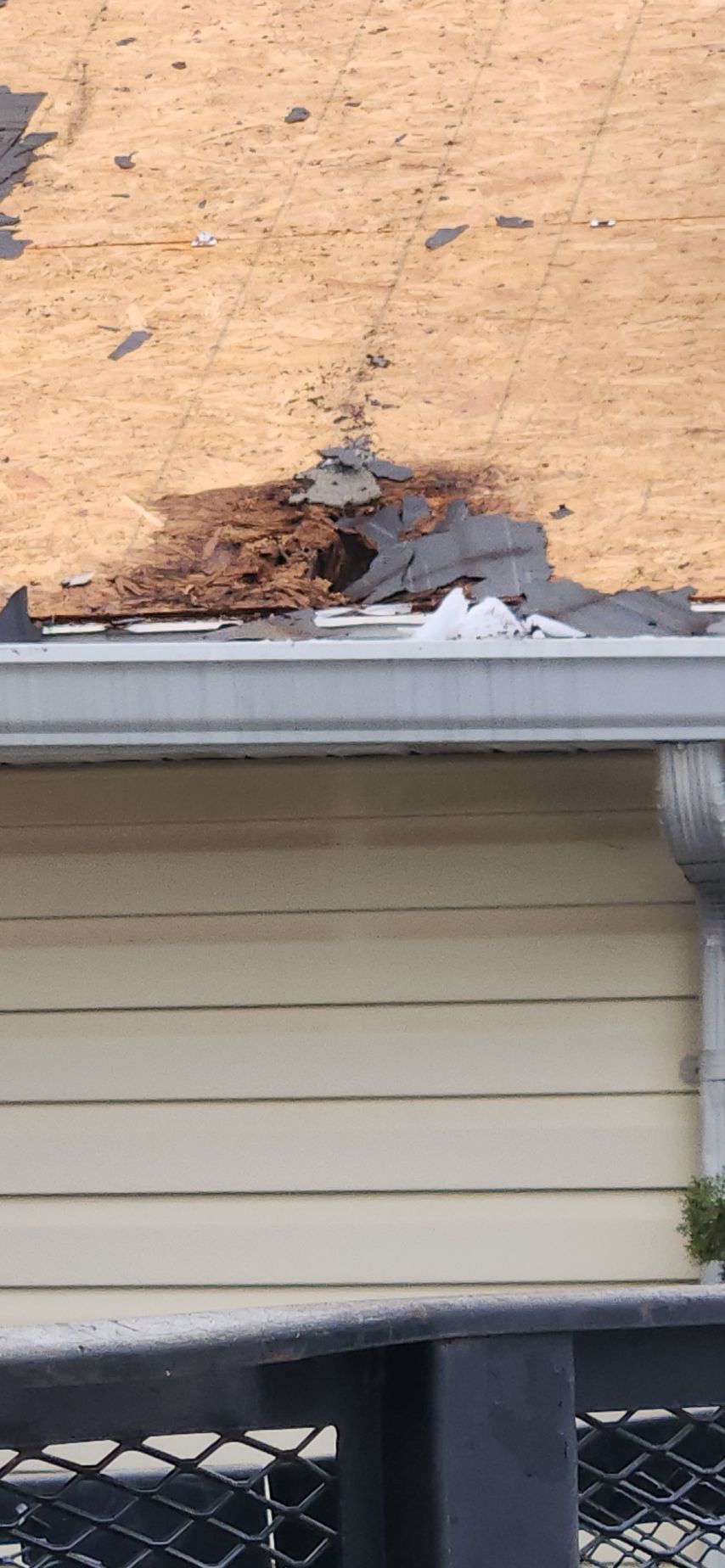 A roof with a hole in it and a gutter on a house.