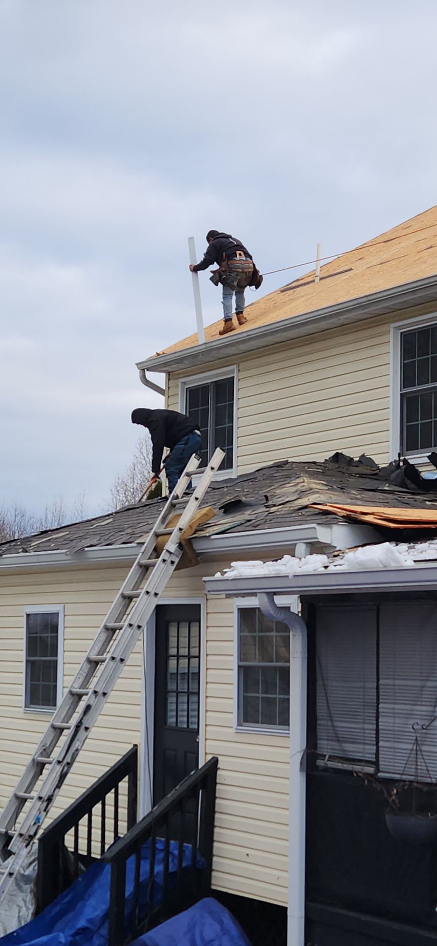 Two men are working on the roof of a house.