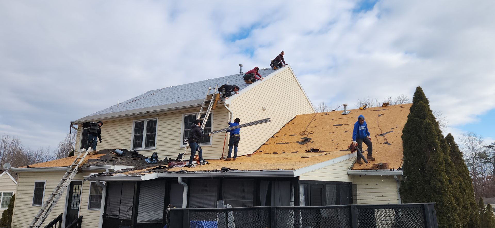 A group of people are working on the roof of a house.