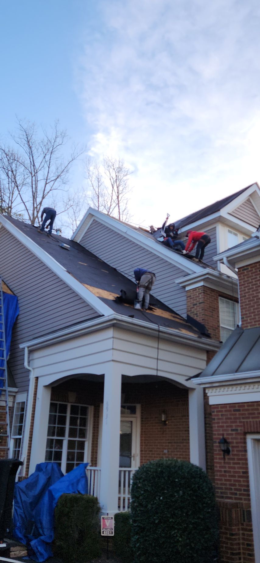 A group of people are working on the roof of a house.