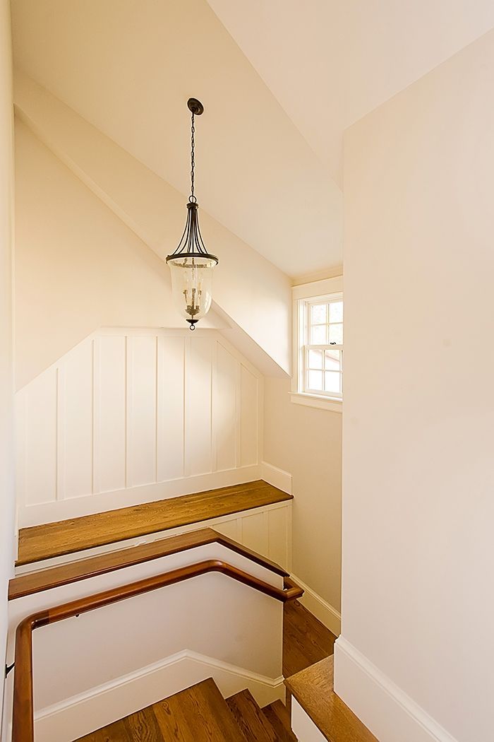 A staircase with a wooden handrail and steps, leading up to a landing with a built-in bench and a hanging lantern light.