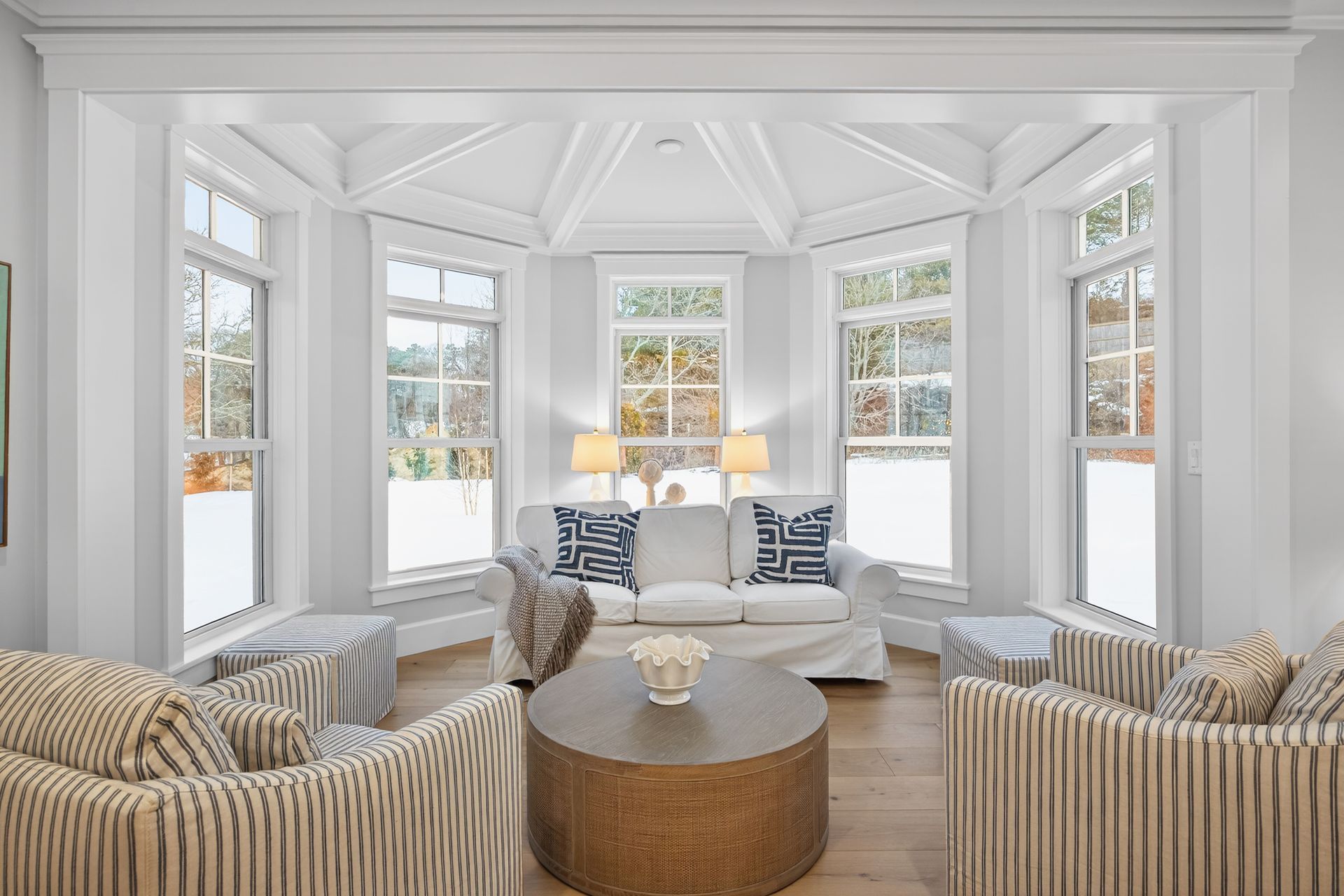 Living room with white walls, arched windows, light-colored furniture, and a round coffee table.
