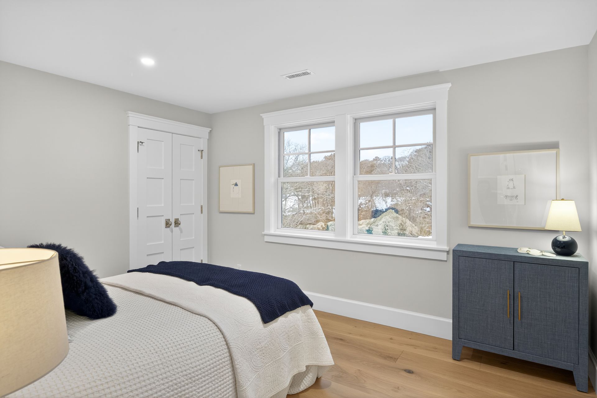 Bedroom with white walls, window, wooden floor, and blue accents.
