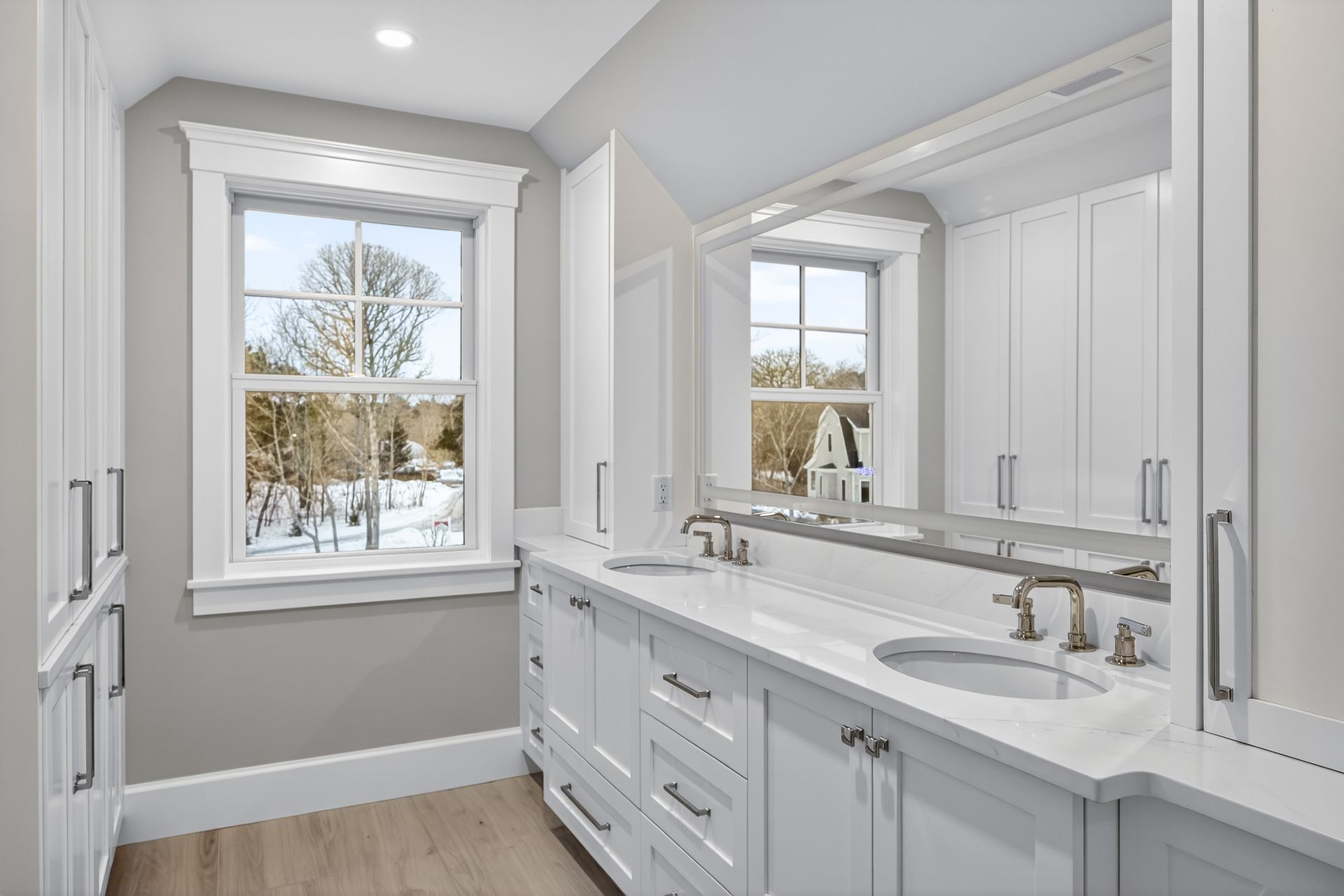 White bathroom with a double vanity, window, and cabinetry.