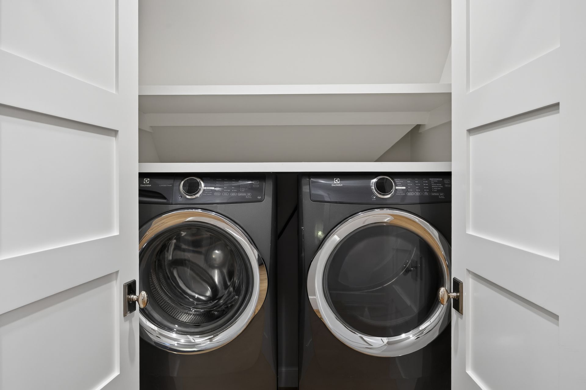 Laundry closet with closed white doors revealing a dark gray washer and dryer.