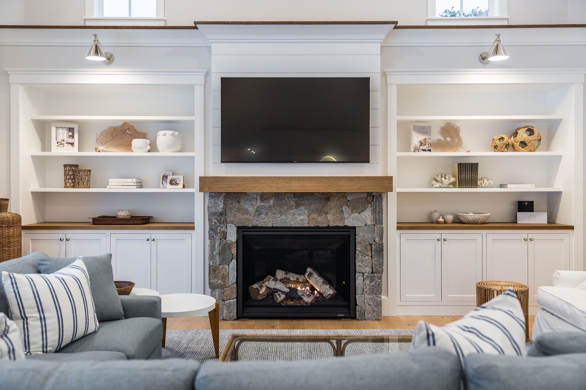 Living room with fireplace, built-in shelves, TV, and blue couches.