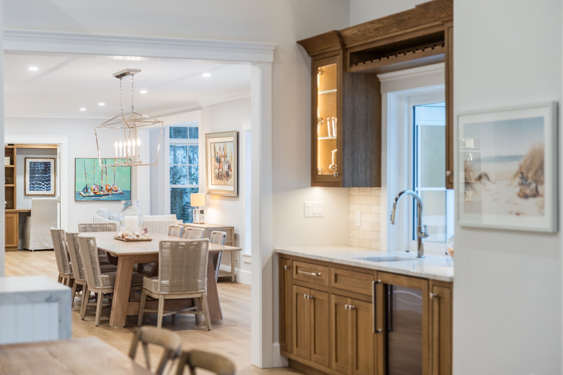 Kitchen and dining room open to each other; wooden cabinets, countertop, table with chairs, and wall art.