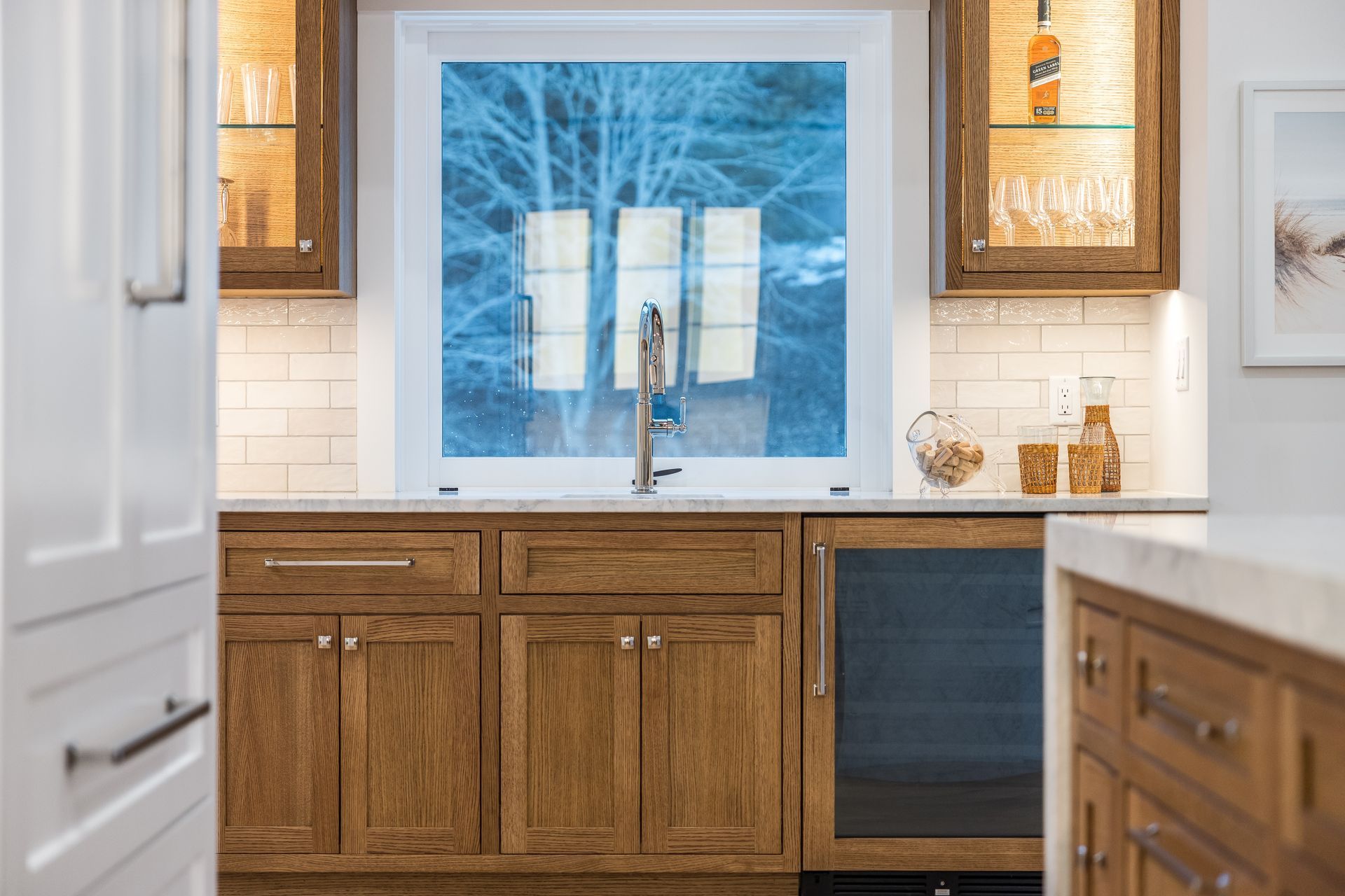 Kitchen with wooden cabinets, a sink under a window, and a wine fridge.