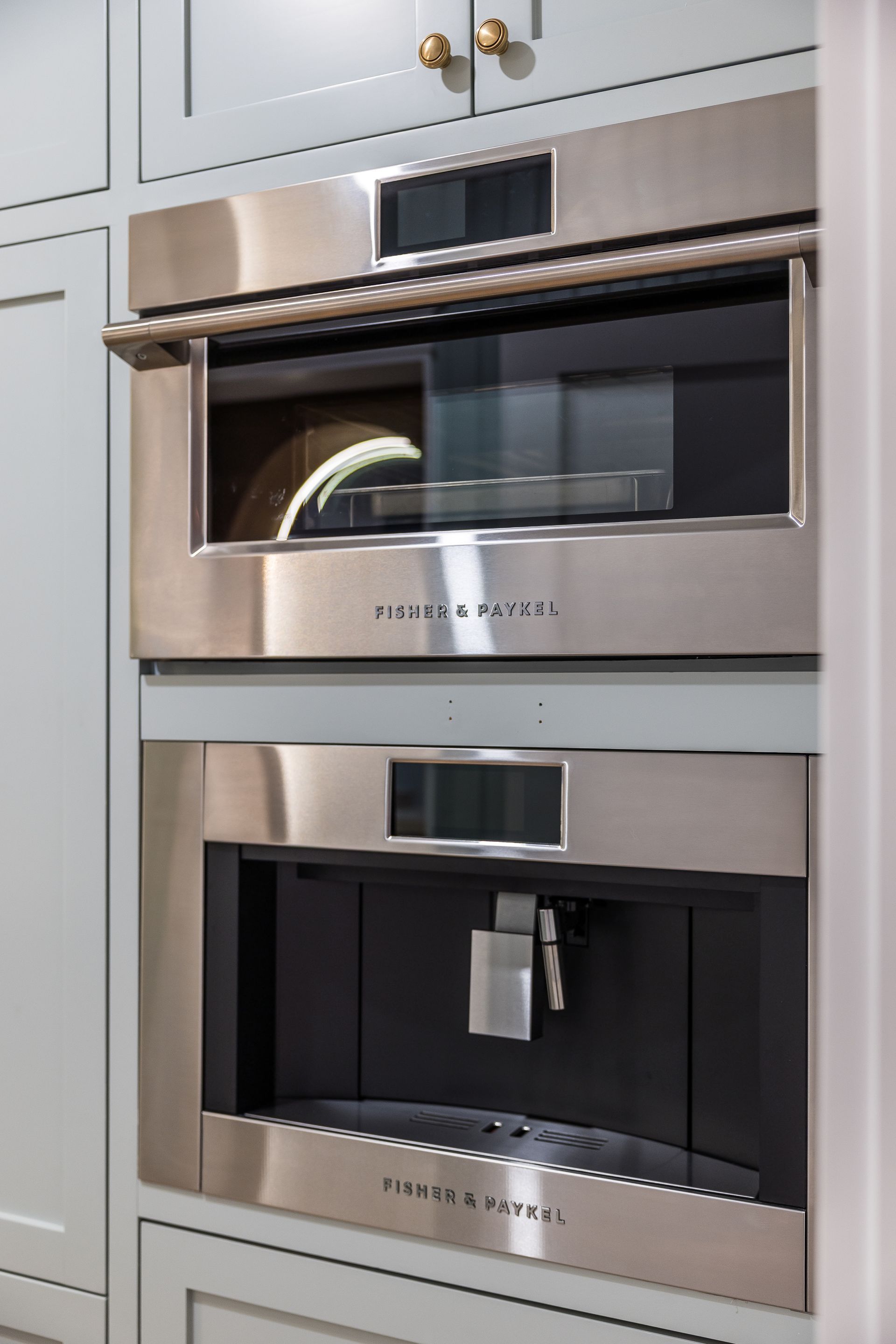 Built-in stainless steel oven and coffee maker in a light blue cabinet.