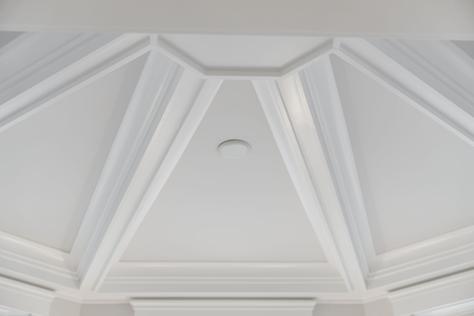 White coffered ceiling with geometric panels and recessed lighting.