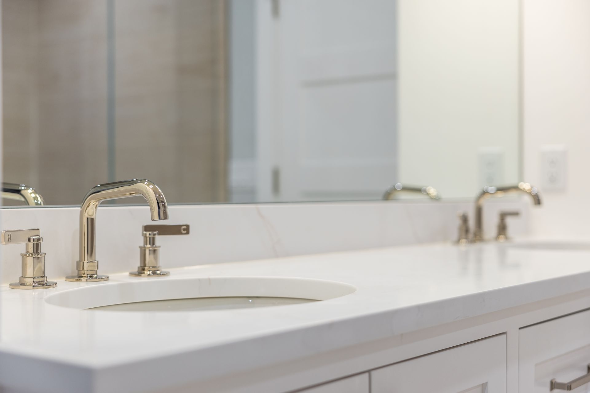 Bathroom countertop with silver fixtures, oval sink, and large mirror.