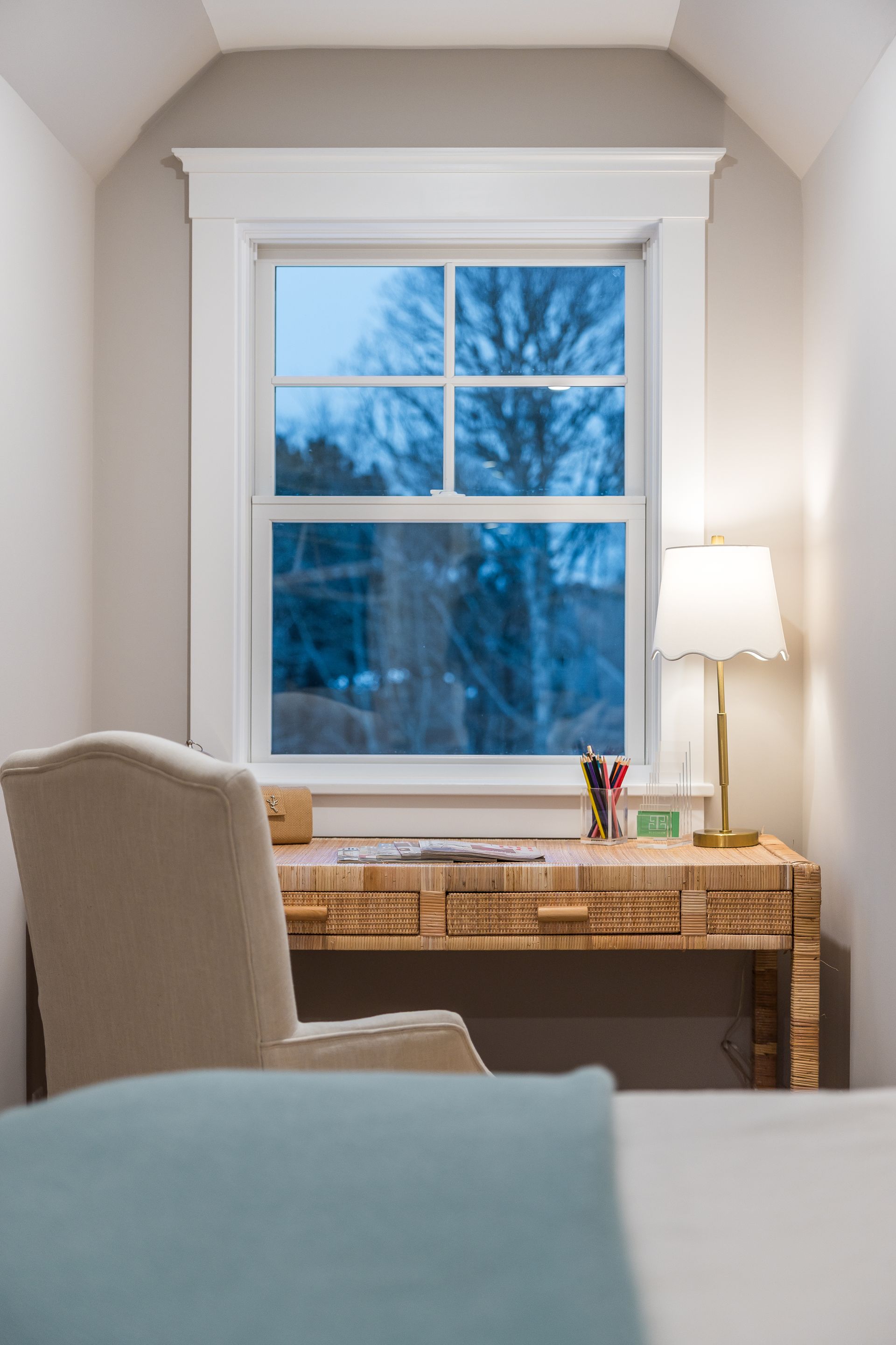 Desk near window in a room with chair, lamp, and neutral colors; outdoor view through window.