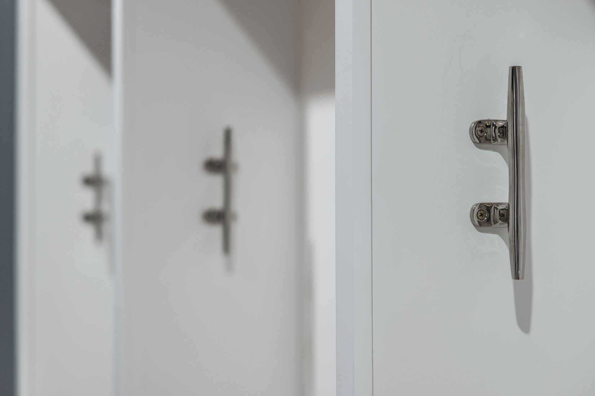 White locker doors with stainless steel boat cleats as handles.