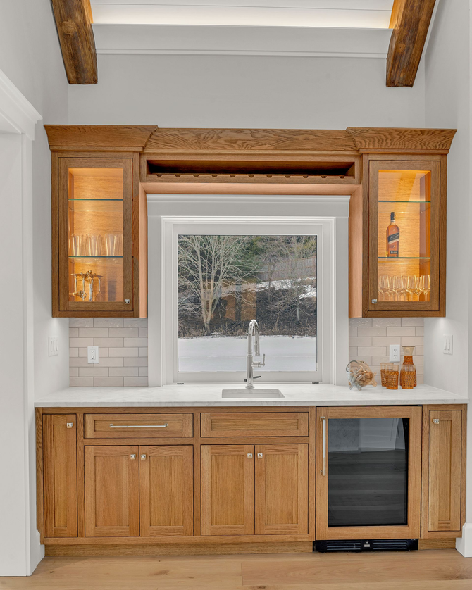 A two-story light gray house with dark shingles, a pool, and a lush green lawn on a sunny day.