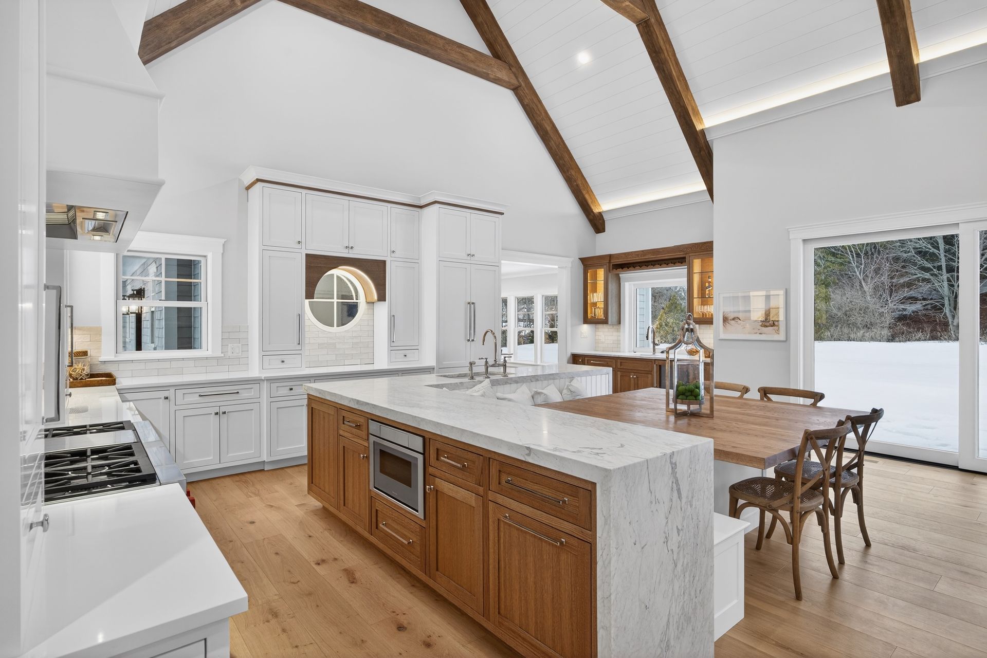 Spacious, modern kitchen with white and wood cabinets, large island, and dining area.