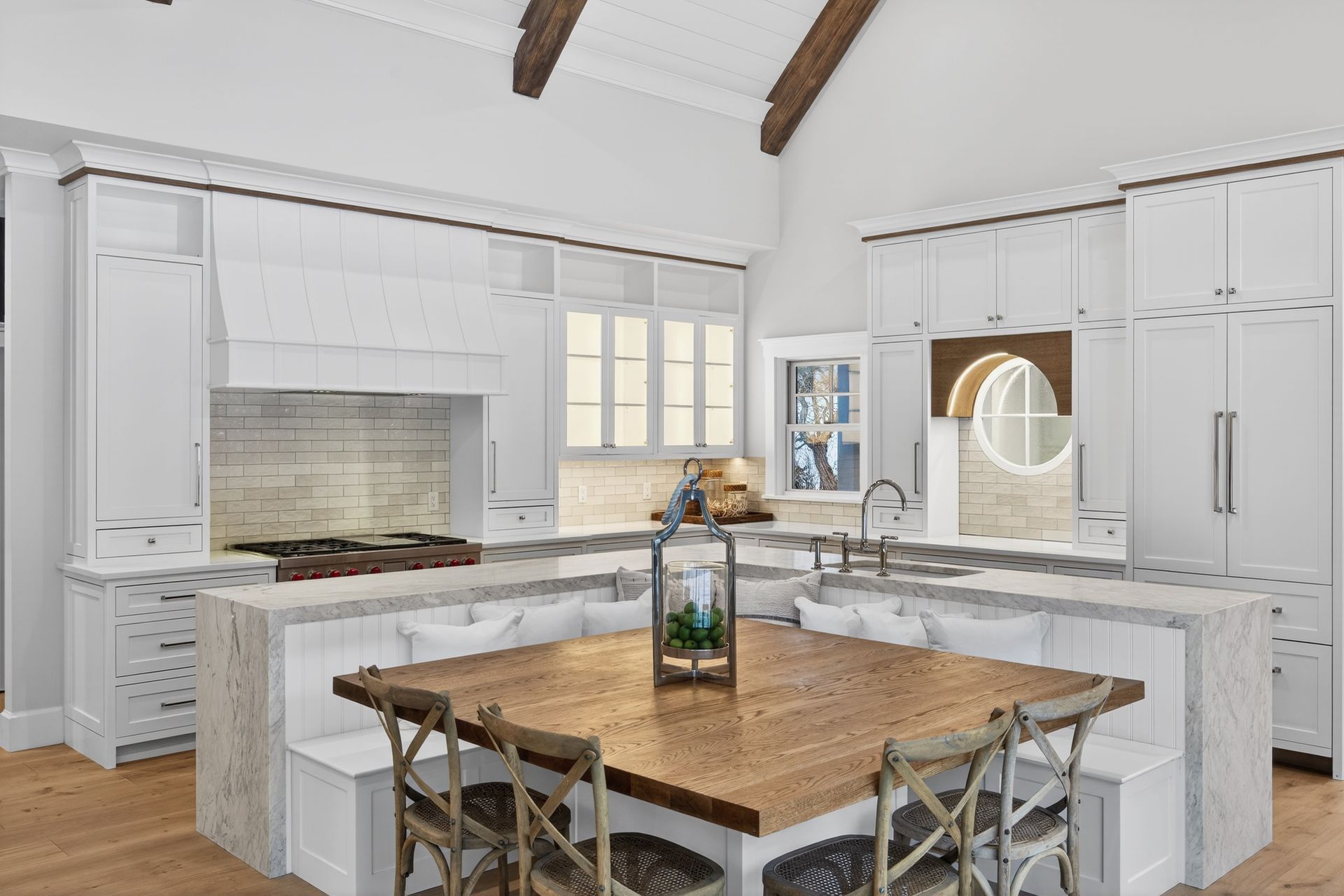 Kitchen with white cabinets, granite countertops, a wooden table, and a built-in seating area.
