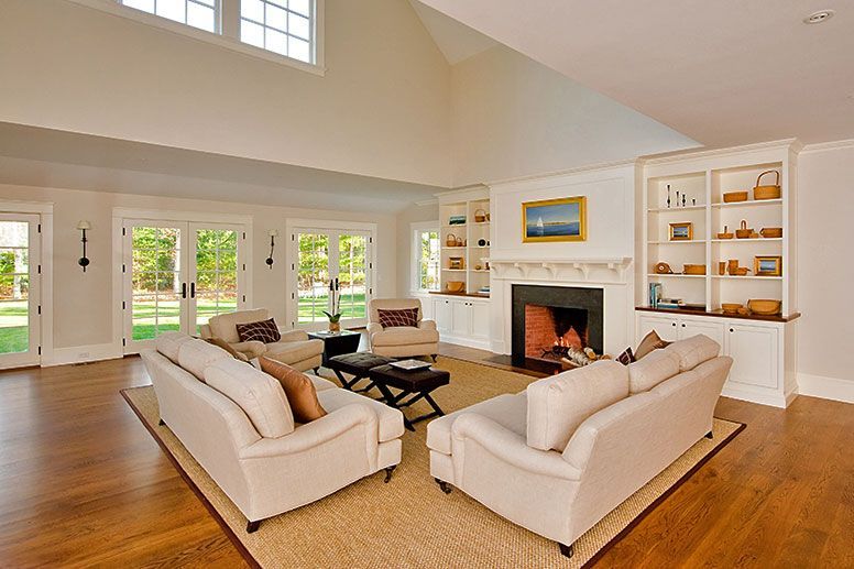 Spacious living room with two cream sofas facing a fireplace, built-in shelving, and large glass doors to a garden.