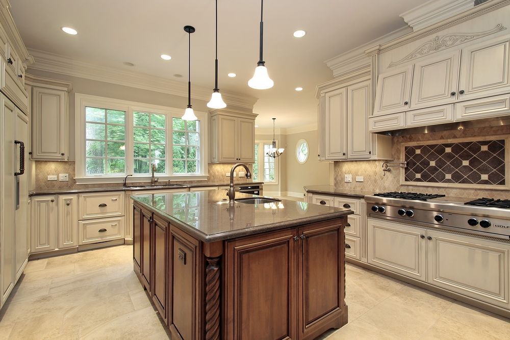 A spacious kitchen with a dark-wood island, cream-colored cabinets, stainless steel appliances, and tile flooring.