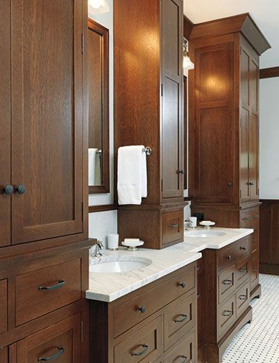 Double bathroom vanity with dark wood cabinets, white marble countertops, and tall storage towers in a tiled room.