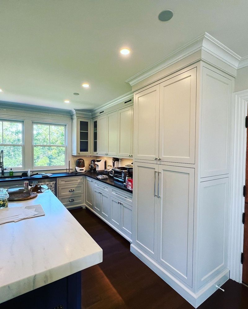 Modern kitchen with white shaker cabinetry, a large white countertop island, and dark hardwood floors.