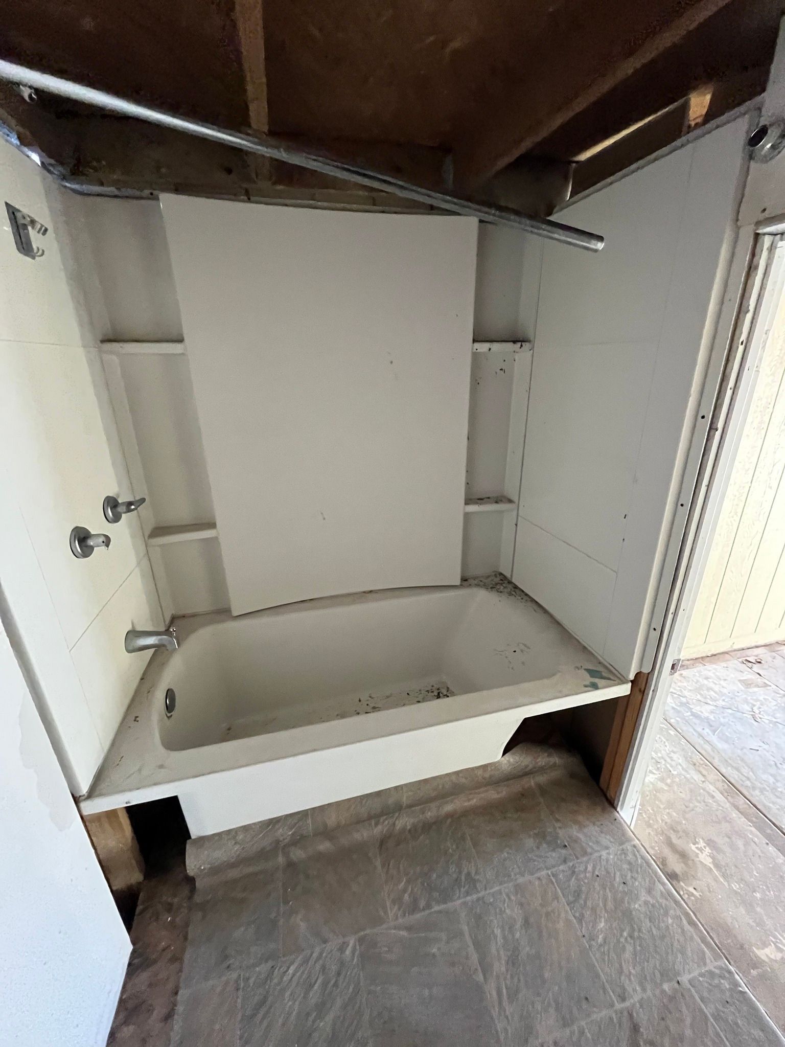 Open cabinet with a large white utility sink and empty shelf in a rough indoor space
