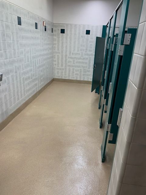 Public restroom stall row with teal partitions and beige floor