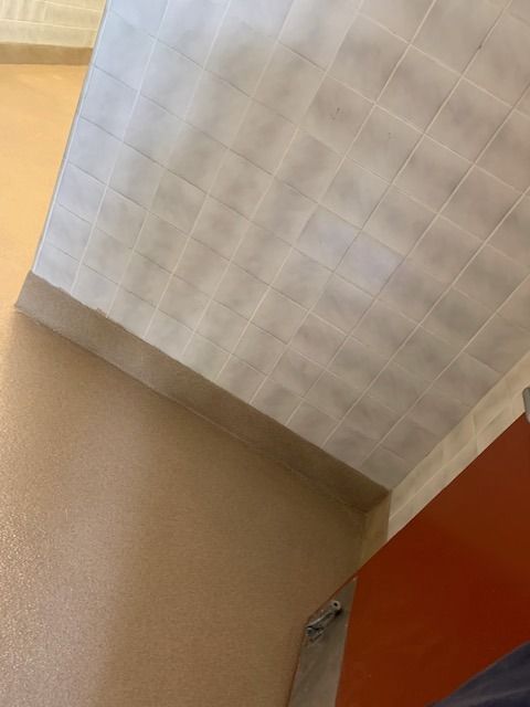 White textured ceiling corner above a tan wall and orange door frame