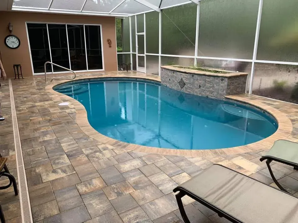 Indoor pool with blue water, brick pavers, and a tiled hot tub.
