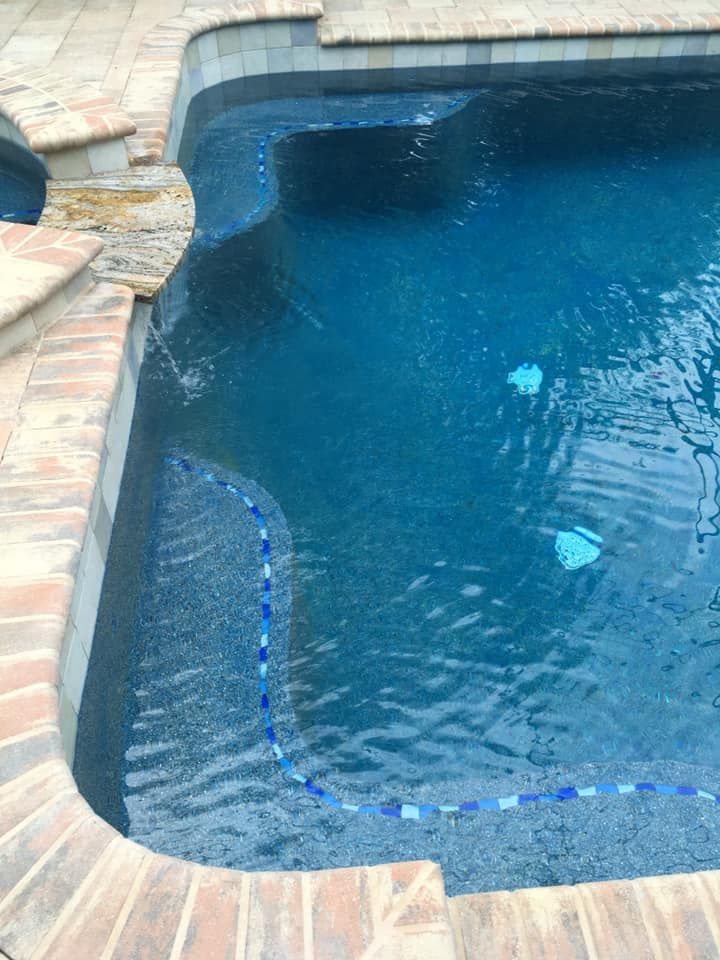 Blue tiled swimming pool with brick coping, water flowing from the edge.