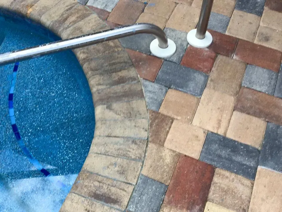 Brick patio surrounding a circular pool with a metal handrail.