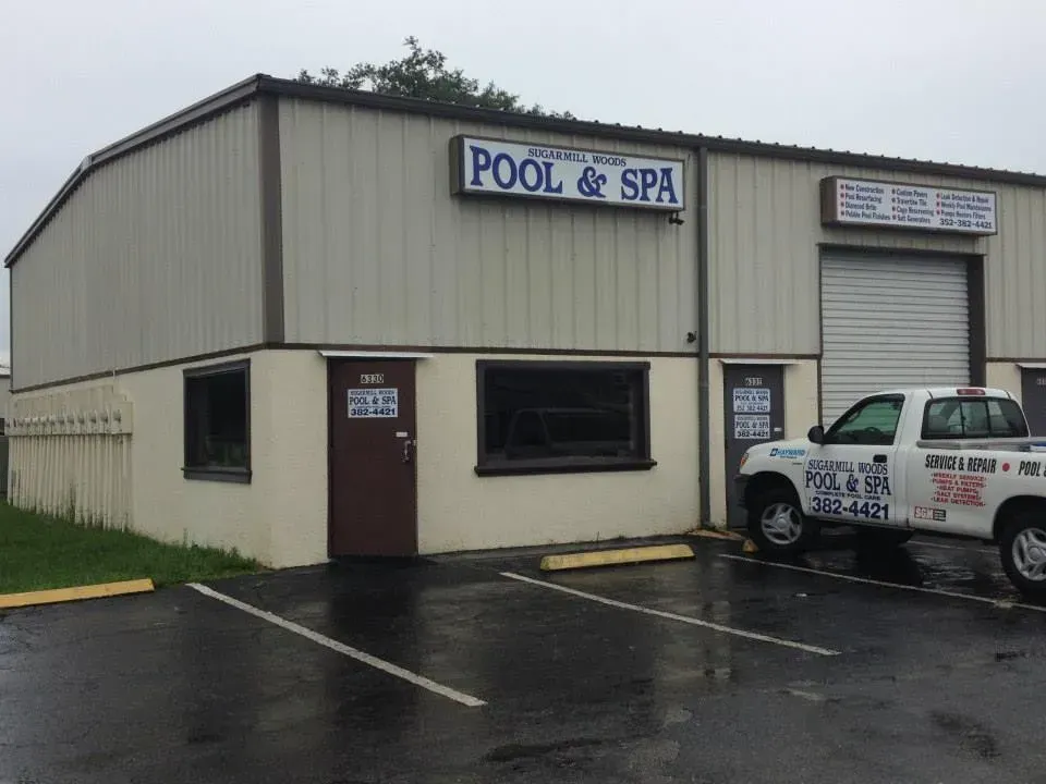 Exterior of a pool and spa supply store with a sign above the entrance and a white truck parked out front.